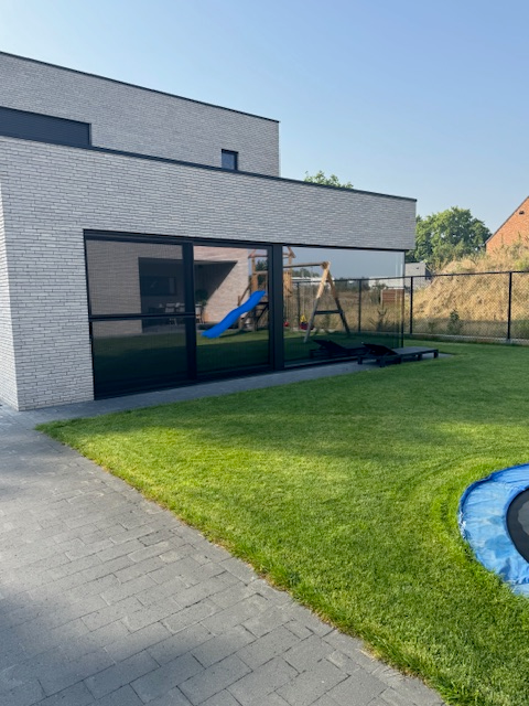 Achterkant van moderne woning afgewerkt met aluminium ramen en schuifdeur