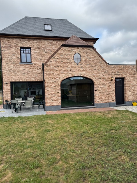 Achterkant van landelijk huis met grote, zwarte, aluminium ramen